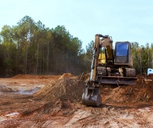 Excavator moving soil and debris during commercial site preparation